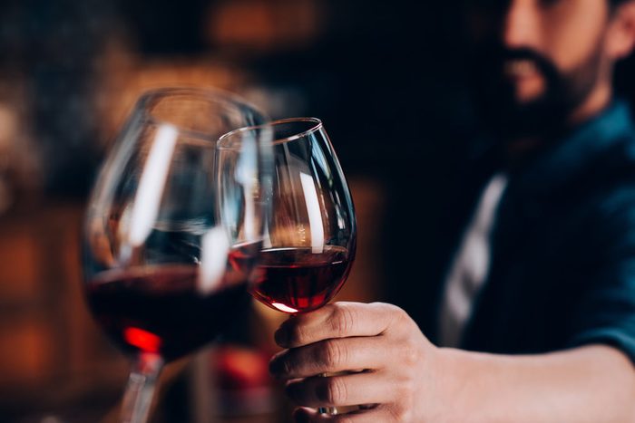 close-up partial view of friends clinking glasses of red wine
