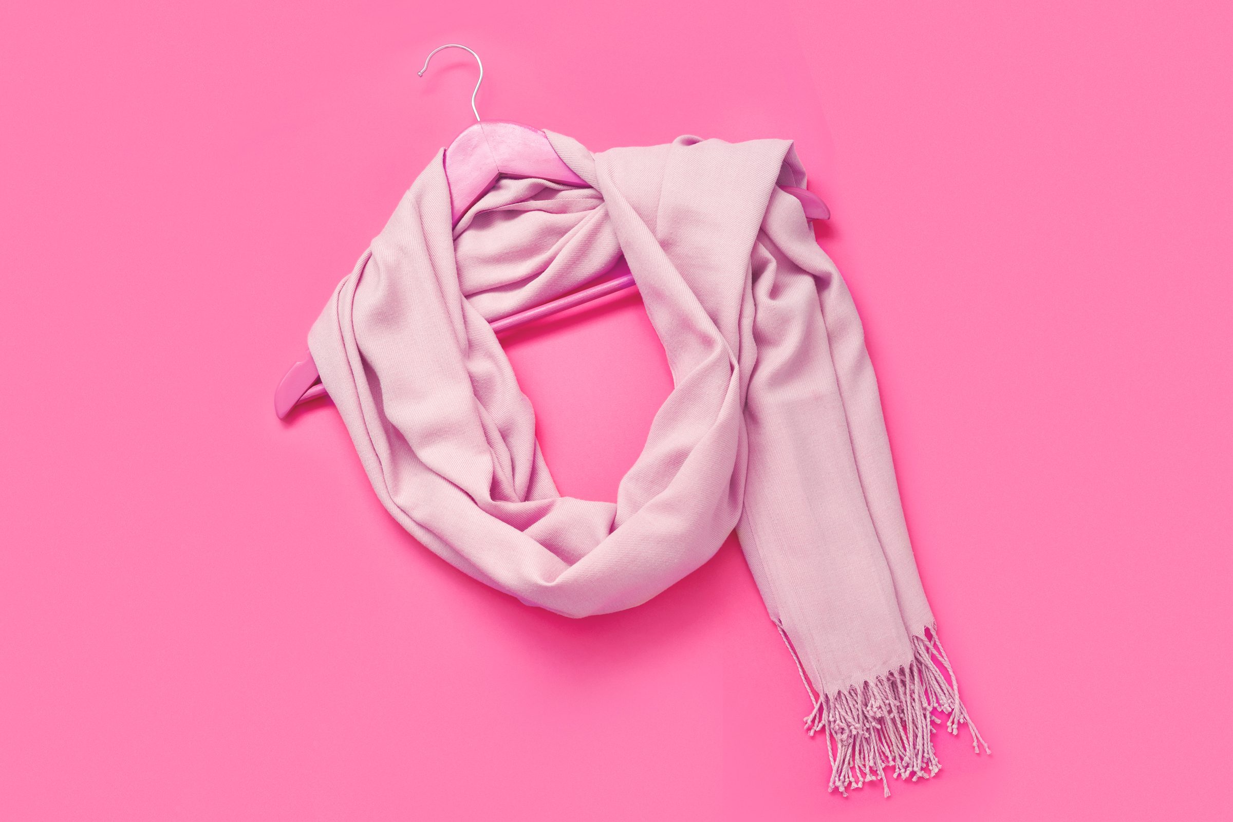 large scarf wrap on a hanger on a pink background