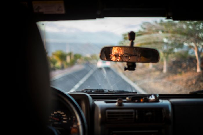 adult senior woman drive the car. inside point of view with focus on the mirror to see her concentrated face and expression while driving with care. transport and life concept