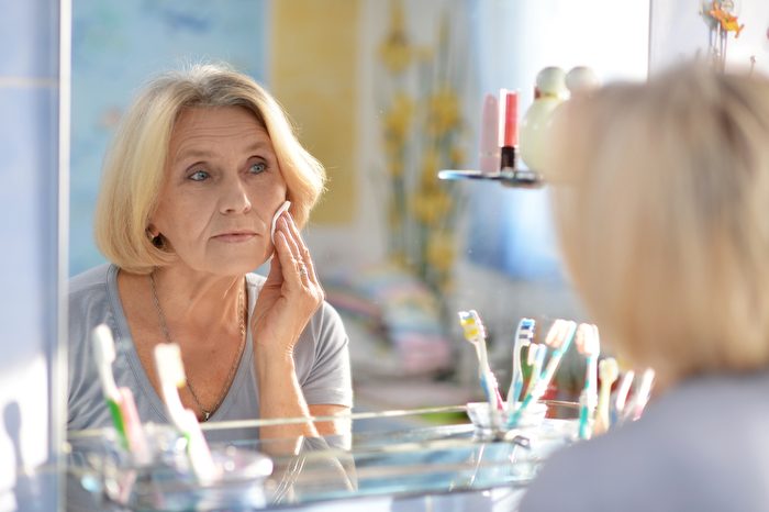 beautiful elderly woman doing make-up in the bathroom