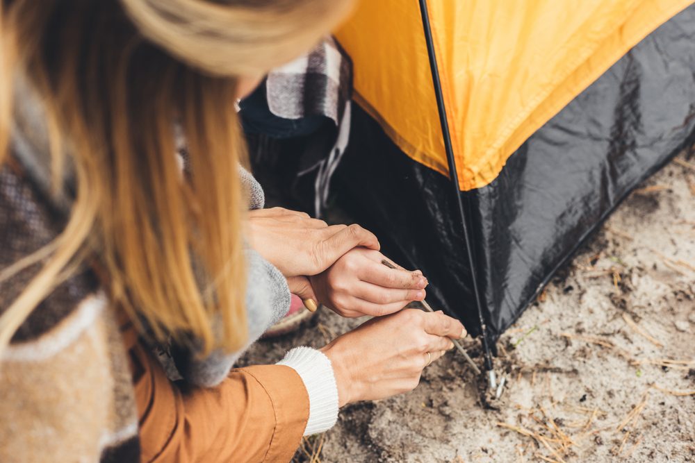 cropped shot of mother and kid installing camping tent