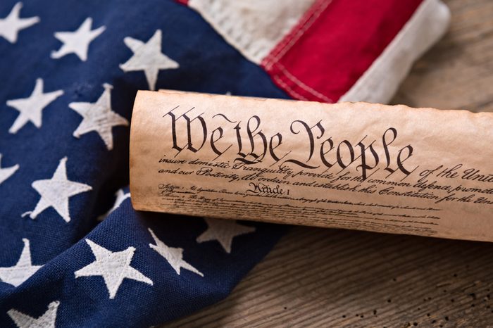 United States Constitution, rolled in a scroll on a vintage American flag and rustic wooden board