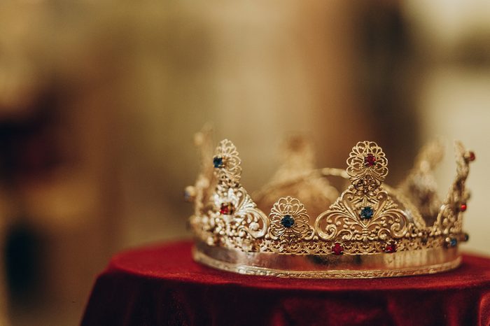 golden crown with gemstones on red napkin on altar in church. traditional wedding ceremony, space for text. religion