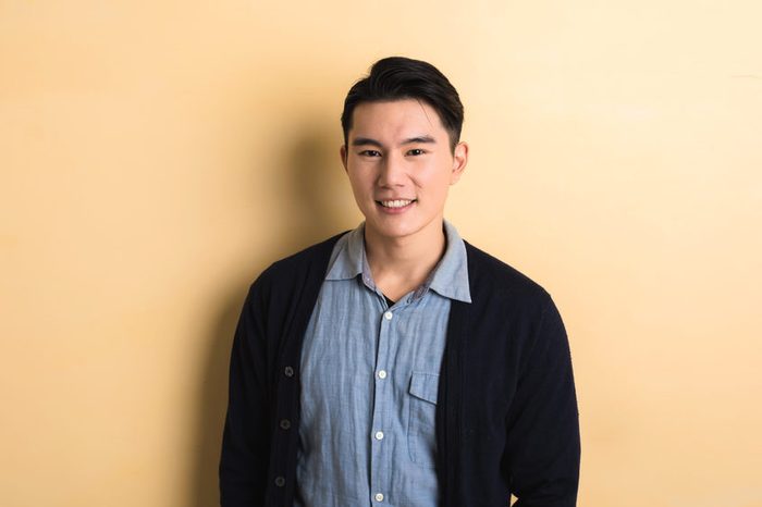 handsome Asian young man smile in the studio yellow background