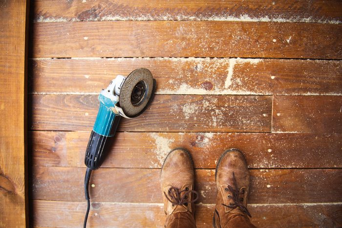 Electric grinder machine left on dusty wooden flooring with wood shavings