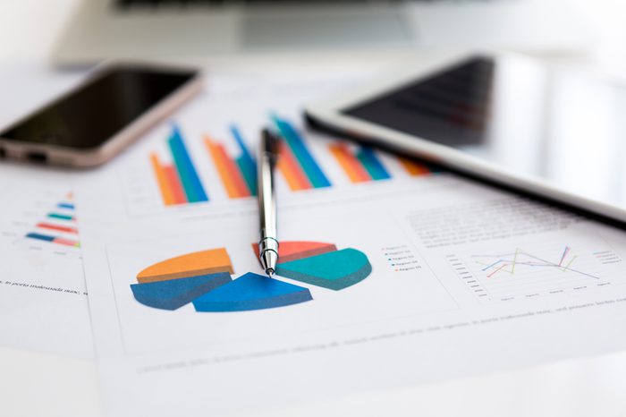 Financial charts on the table with tablet phone and pen