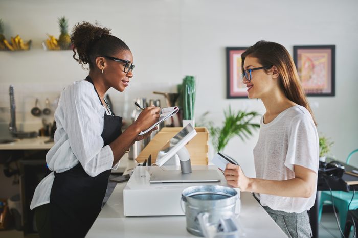friendly african american waitress taking order on notepad from customer