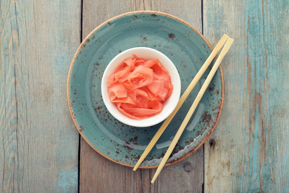 Pickled ginger with wooden chopsticks on plate top view