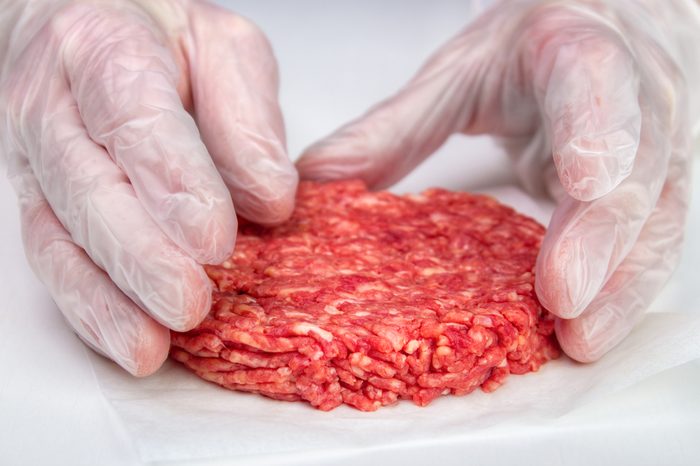 Hand shaping burger patty with vinyl gloves for hygiene