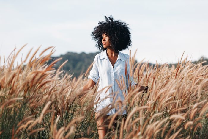 cheerful african american young woman on the field at sunset