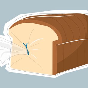 A loaf of sliced bread wrapped tightly in transparent plastic, tied with a blue twist tie, against a plain background.