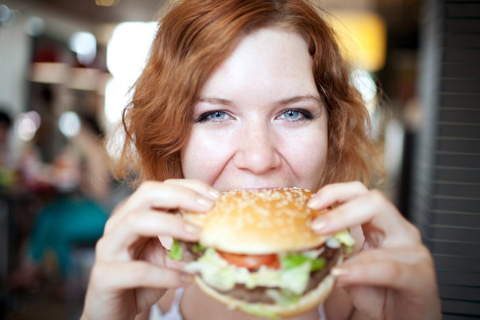 beauty woman in cafe eating hamburger