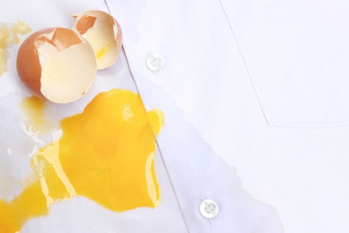 Dirty egg stain on white shirt fabric in kitchen, daily life stains in house work
