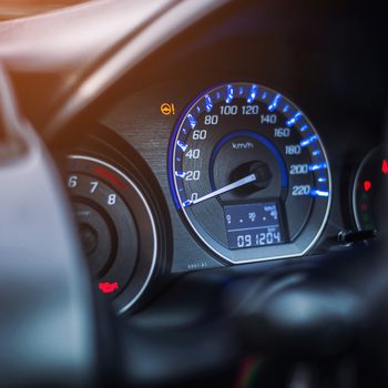 Speedometer pointing to zero, surrounded by glowing blue lights, within a vehicle dashboard; odometer reads 091204, with warning lights present.