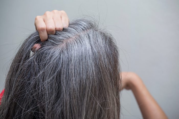 woman is checking white hair white looking at the mirror