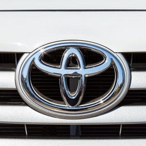 A shiny chrome Toyota emblem is displayed on the front grille of a white vehicle.
