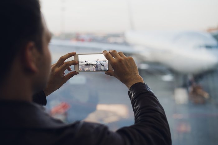 Man hand take picture of airplane using cellphone. Tourism concept photo
