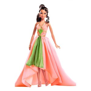 Doll stands elegantly in a pink and green gown, hands on hips, against a white backdrop.