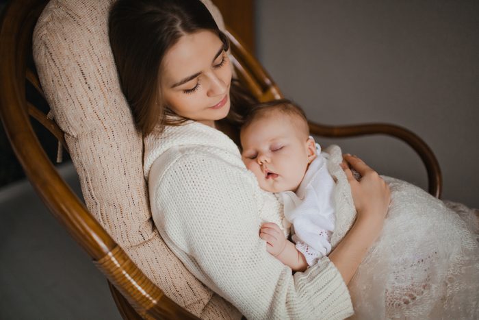 young mother holding her newborn baby sitting in armchair