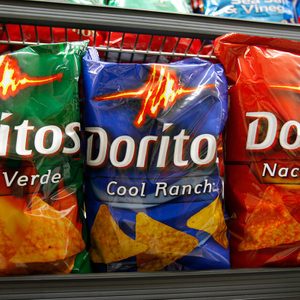 Three Doritos bags sit on a store shelf: Salsa Verde (green), Cool Ranch (blue), Nacho Cheese (red).
