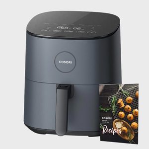 Air fryer sits idle beside a recipe booklet, displaying a sleek design against a plain backdrop.