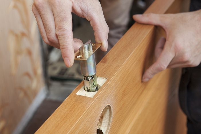 Installation locked interior door knobs, close-up woodworker hands install lock.