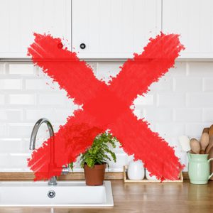 Red X marks a kitchen counter with a potted plant, sink, cutting boards, and utensils, against a white tiled backsplash.