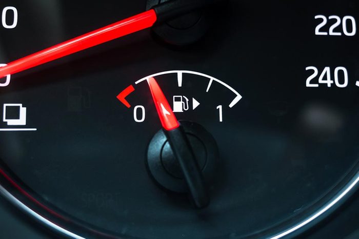 Fuel gauge mounted in round modern car speedometer shows low level of gasoline