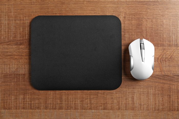 Blank mat and wireless mouse on wooden background