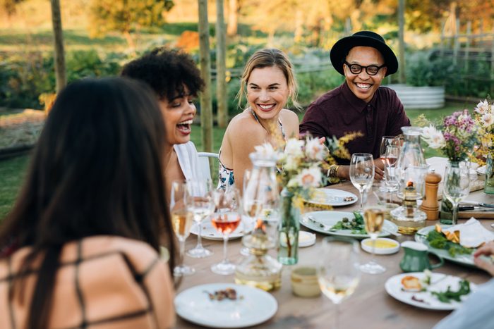 Group of friends enjoying outdoor party in home garden. Millennials enjoying summer meal at restaurant.