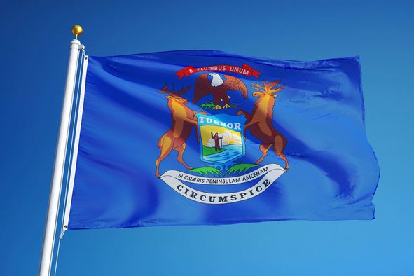 Michigan (U.S. state) flag waving against clear blue sky, close up, isolated with clipping path mask alpha channel transparency, perfect for film, news, composition