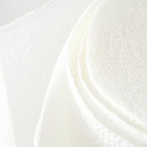 A roll of white toilet paper unravels against a plain, light background.