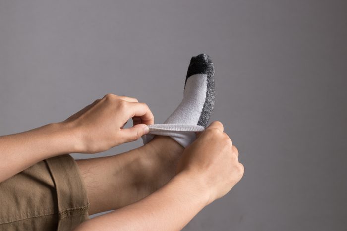 A hand do some action to put a sock on a foot.