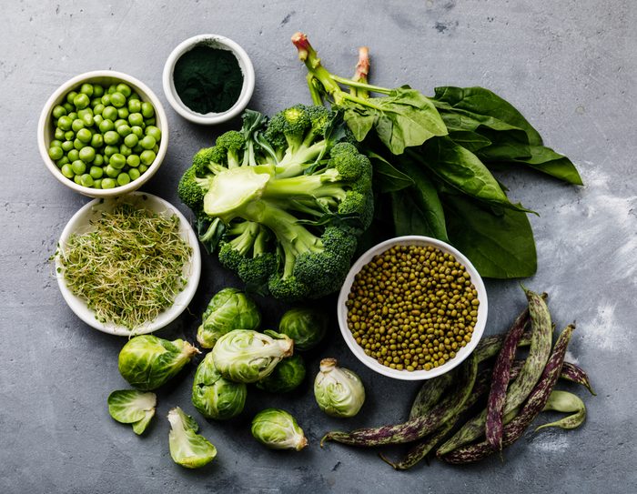 Healthy Green food Clean eating selection Protein source for vegetarians: brussels sprouts, broccoli, spinach, spirulina, green peas on gray concrete background