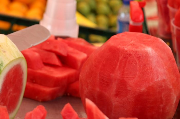 Man cuts the watermelon with a knife to prepare the fruit salad for sale