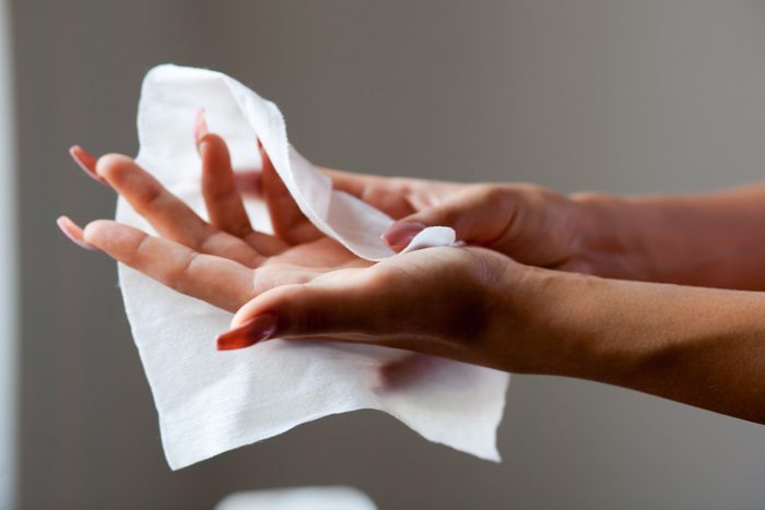 Young woman cleaning hands with wet wipes