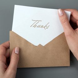 Hands holding an open brown envelope revealing a card with 