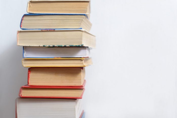 Stack of different old books on a table against a white wall background, reading concept