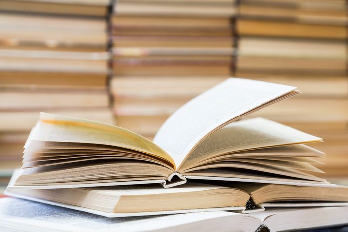 A stack of books with colorful covers. The library or bookstore. Books or textbooks. Education and reading. Open book in the foreground.