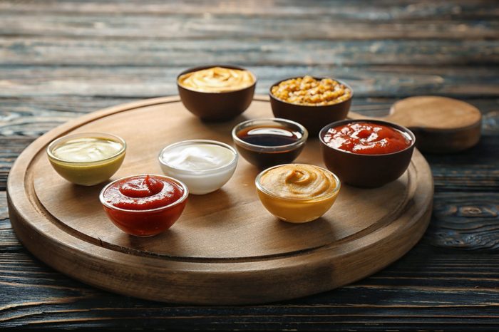 Board with different sauces on wooden background
