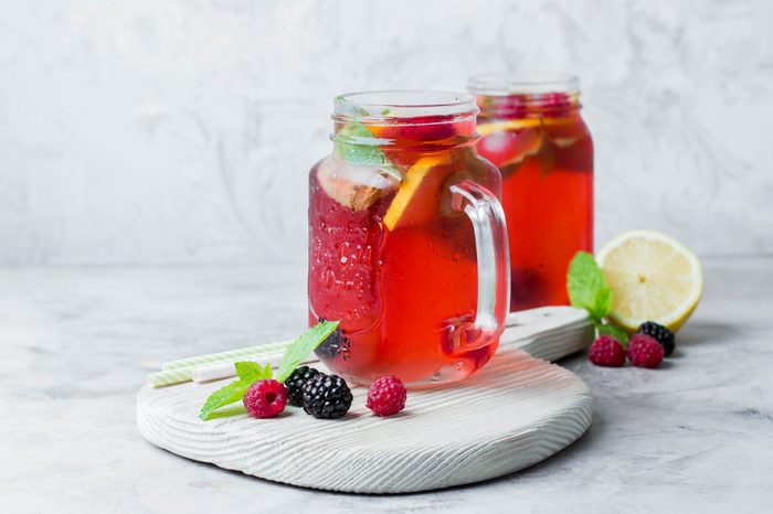 Summer Berry Drink. Lemonade with raspberry and blackberry with lemon, mint in mason jar on gray stone table background. Copy space, horizontal image