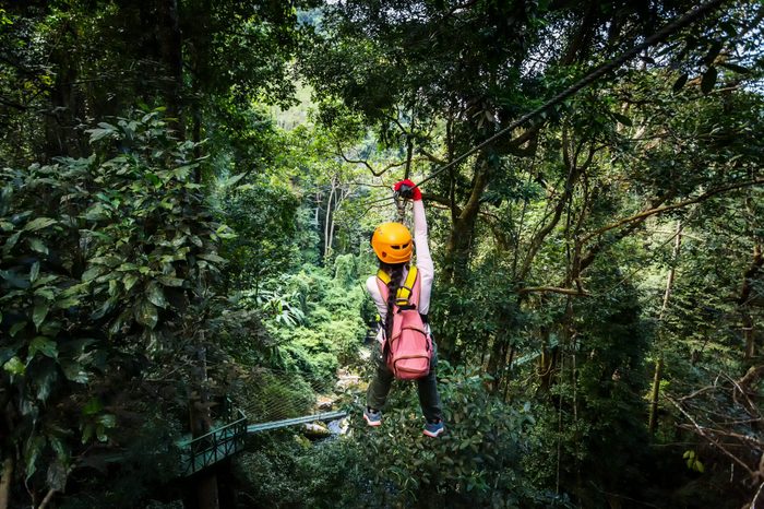 TOURIST adult wearing casual clothes Zip Line On Focus FOREST TRIP fun.