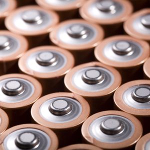 Several AA batteries are tightly arranged in a grid, highlighting their positive terminals in a close-up view.
