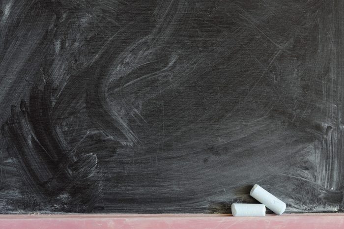 detailed black chalkboard fragment with two chalk pieces