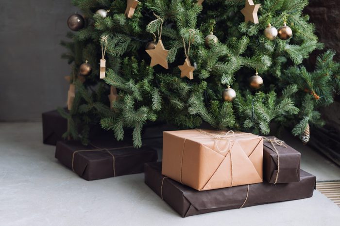 Christmas tree with wooden rustic decorations and presents under it in loft interior.