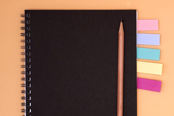 notebook with colored flags and pencil