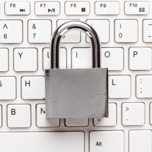 A silver padlock rests on a white computer keyboard, symbolizing digital security.