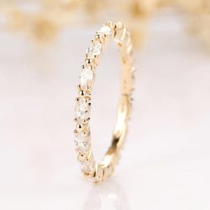 Gold ring showcases marquise-cut diamonds encircling it, resting on a glossy surface, with a blurred golden background.