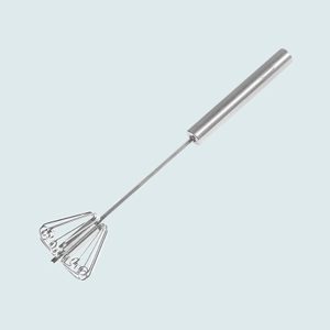 A stainless steel rotary whisk rests still on a plain, light blue background.
