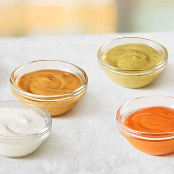 Bowls, containing colorful sauces, are arranged on a light countertop.